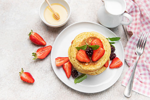 Stacked pancakes with fresh berries and honey, a Food & Drink Photo by Olena Rudo