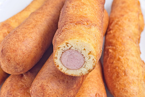 Heap of corn dogs on white plate, served with ketchup, vertical closeup, a Food & Drink Photo by iuliia_n