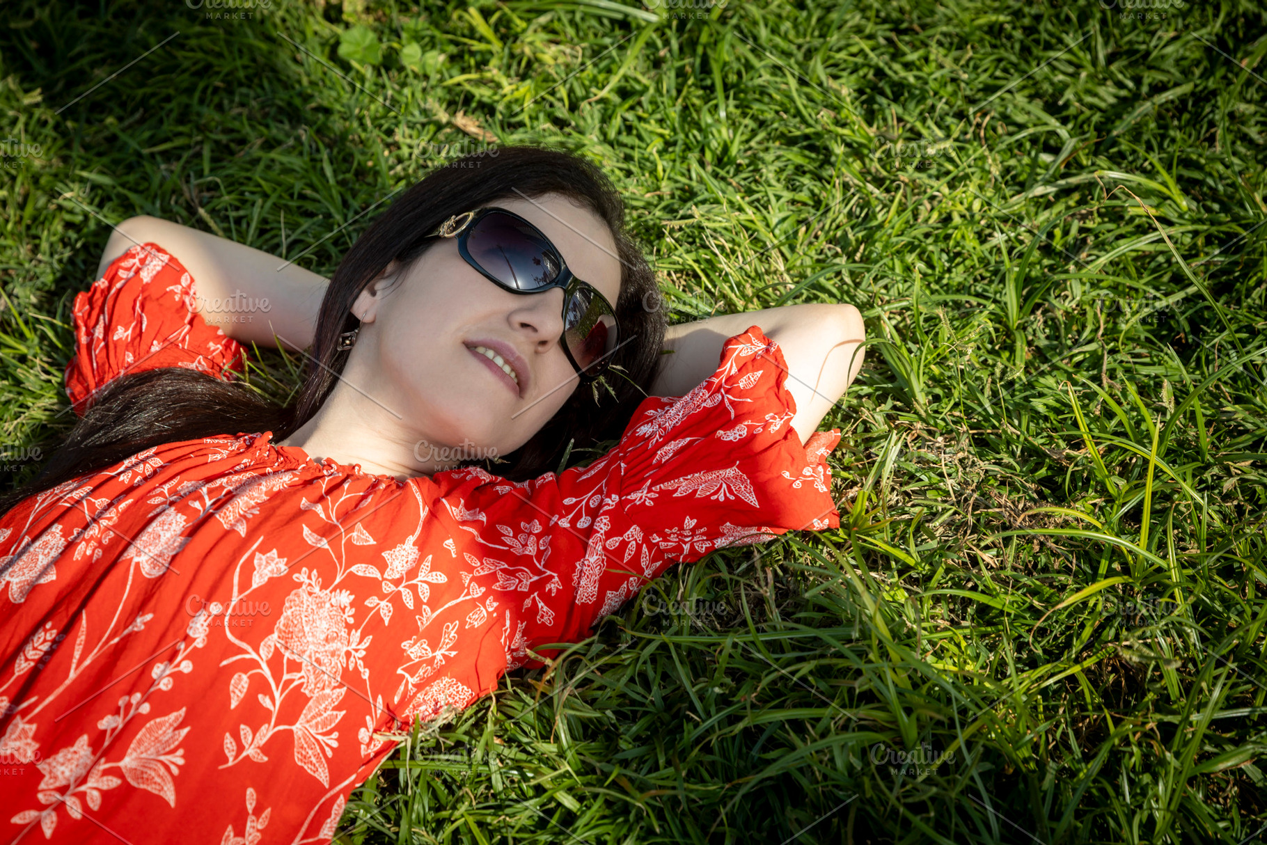 Woman in a red floral dress and sunglasses relaxing on a sunny p, a Person Photo by Imaginarium