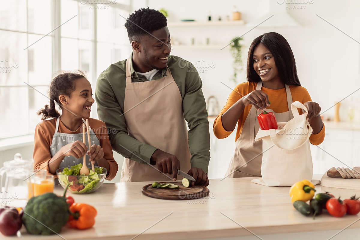 Cheerful Black Family Cooking Making Vegetable Salad In Modern Kitchen, a Photo by Prostock-Studio (Photo 1 of 2)