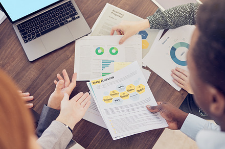 Business, group and above for data on chart, laptop and graph for analytics, finance and desk. Meeting, teamwork and paper for documents of financial strategy, planning and economy of market on table, a Photo by Peopleimages.com