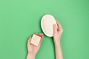 Hands hold soap and loofah sponge