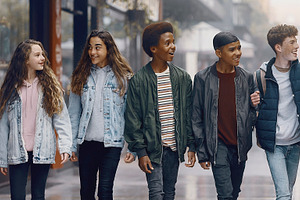 Group of five teenager walking on wet street, a Photo by DanFLCreativo