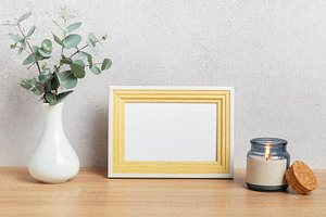 Empty photo frame, eucalyptus leaves and scented candle on woode, a Background Photo by Olena Rudo