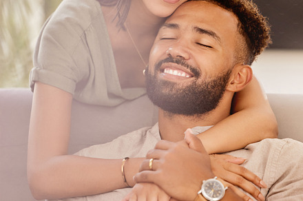 Couple, man and black woman on sofa for hug, love and care in living room to relax while happy. Black man, woman and marriage for romance, embrace and smile together on couch in lounge with happiness, a Photo by Peopleimages.com