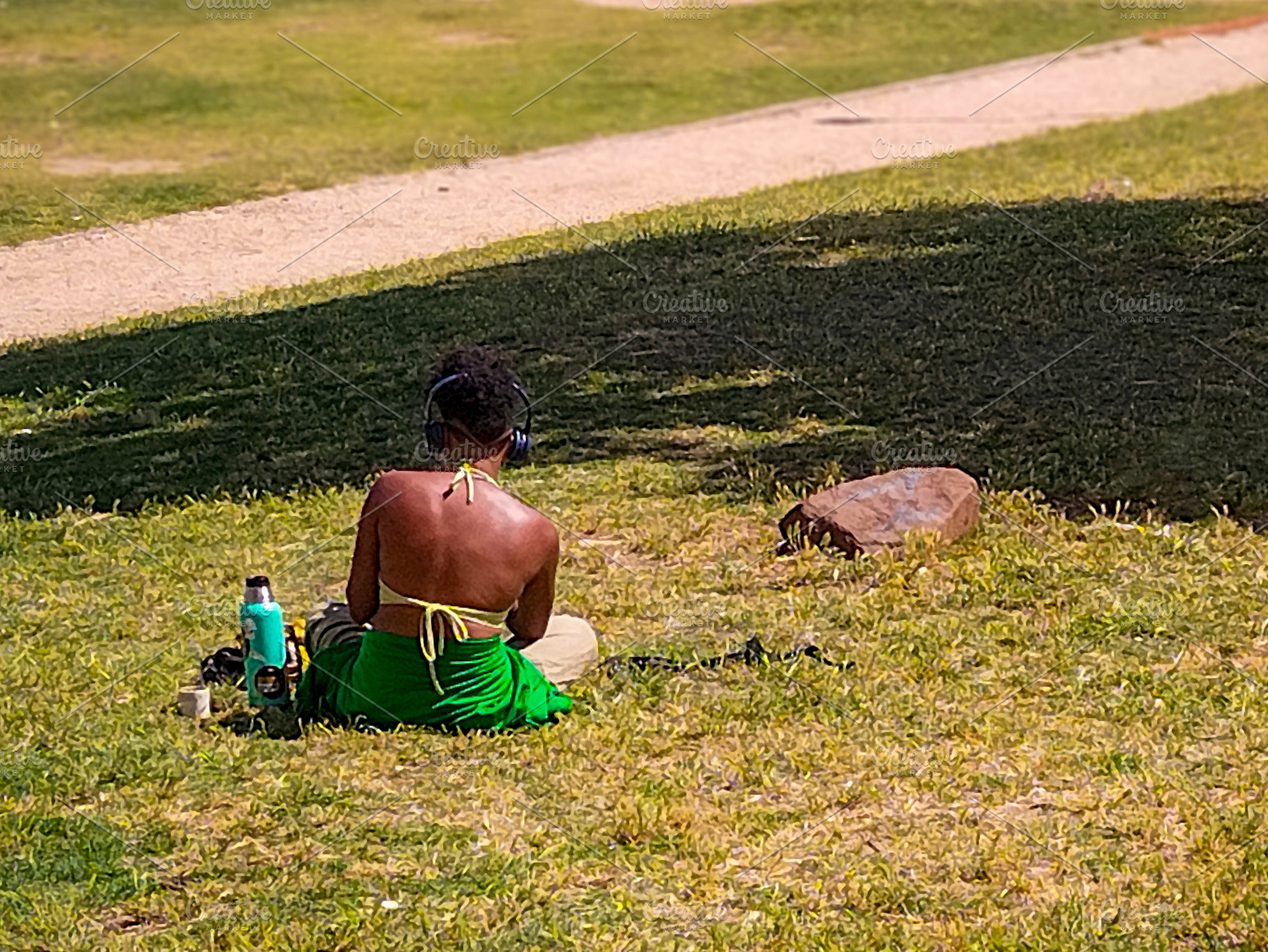 Black woman sitting in sunny urban park from behind, a Person Photo by DanFLCreativo