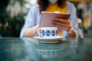 Closeup young woman using digital tablet and drinking coffee