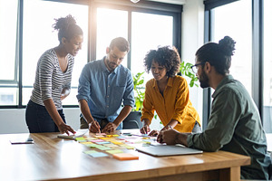 Young professionals engaged in a brainstorming session around a, a Business Photo by DanFLCreativo