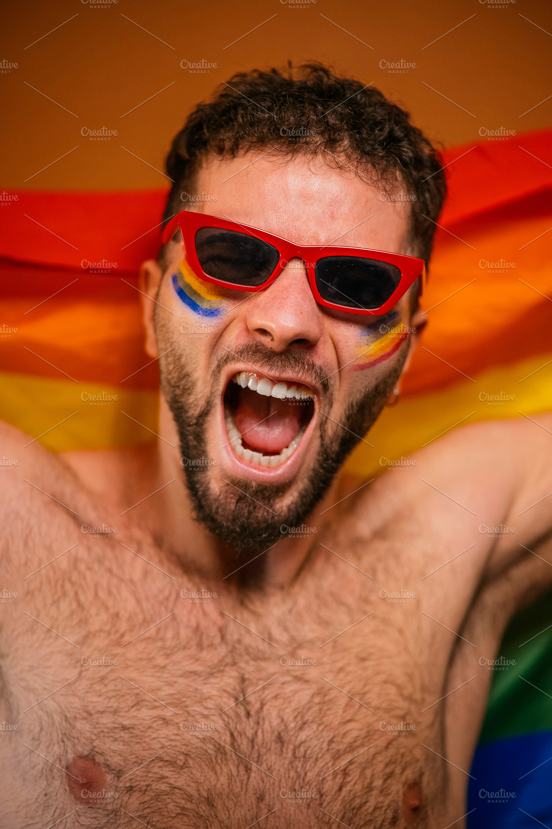 Excited man with face paint celebrating gay pride, a Photo by karrastock