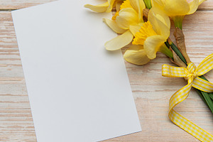 Bouquet of daffodils and blank card lying on wooden table, a Holiday Photo by Olena Rudo