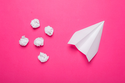 White paper plane on pink background