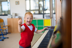 Boy with Down syndrome playing piano, a School & Education Photo by HalfPoint