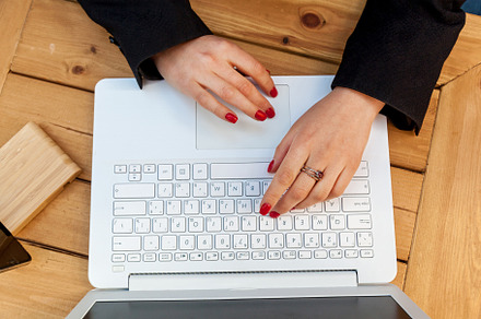 Female hands with red manicure on the background of a white laptop, a Technology Photo by Photostock