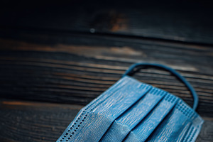 A blue surgical mask mockup lying on a dark wooden surface, a Mask Mockup by Textures & Backgrounds