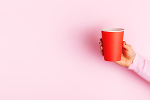 Close-up of hand holding a red paper cup against a pastel pink b, a Food & Drink Photo by Ales Munt