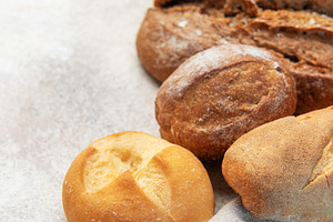 Fresh baked bread, rolls, wheat grain on concrete, a Food & Drink Photo by Olena Rudo