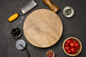 A round empty wooden board on a dark background with tomatoes, o, a Food & Drink Photo by ndanko