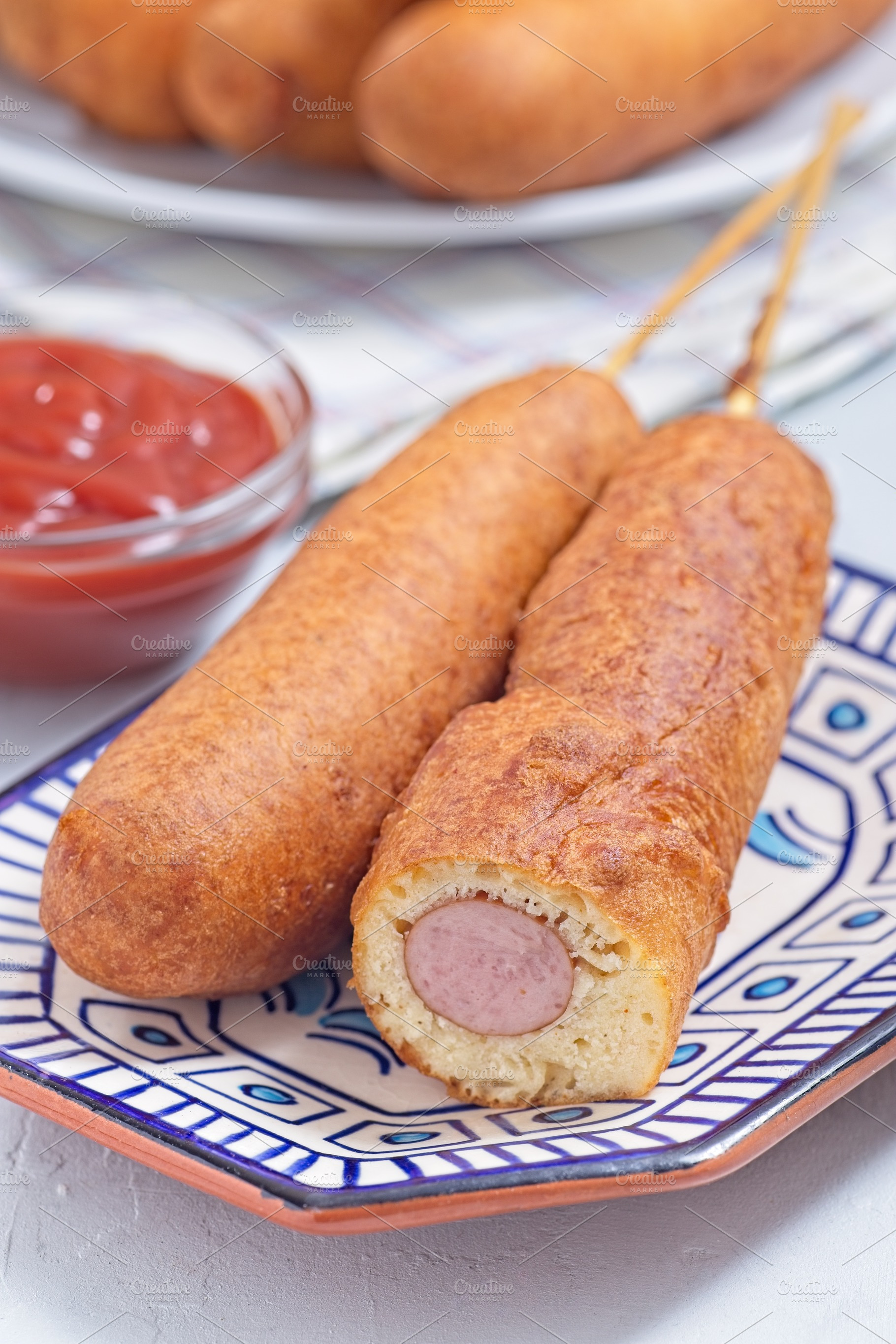 Corn dogs on white blue plate, served with ketchup, vertical closeup, a Food & Drink Photo by iuliia_n