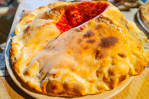 Folded pizza calzone served at restaurant table, a Food & Drink Photo by DanFLCreativo
