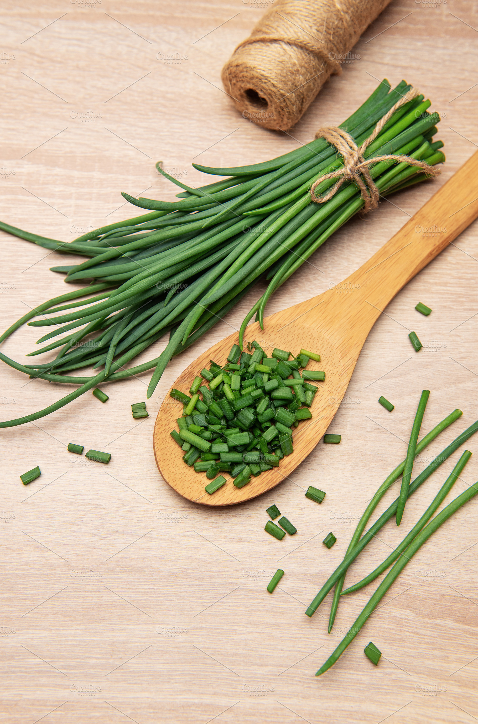 Freshly cut chives resting on wooden spoon and table, a Food & Drink Photo by Olena Rudo