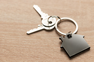 House keys with house shaped keychain on wood