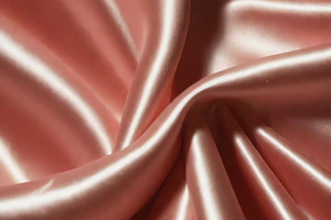 Soft pink satin fabric draping on a surface, showcasing smooth texture and eleg