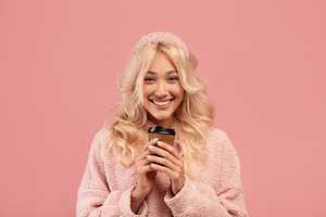Favorite hot drink and break. Happy lady holding takeaway paper cup and smiling, a Photo by Prostock-Studio