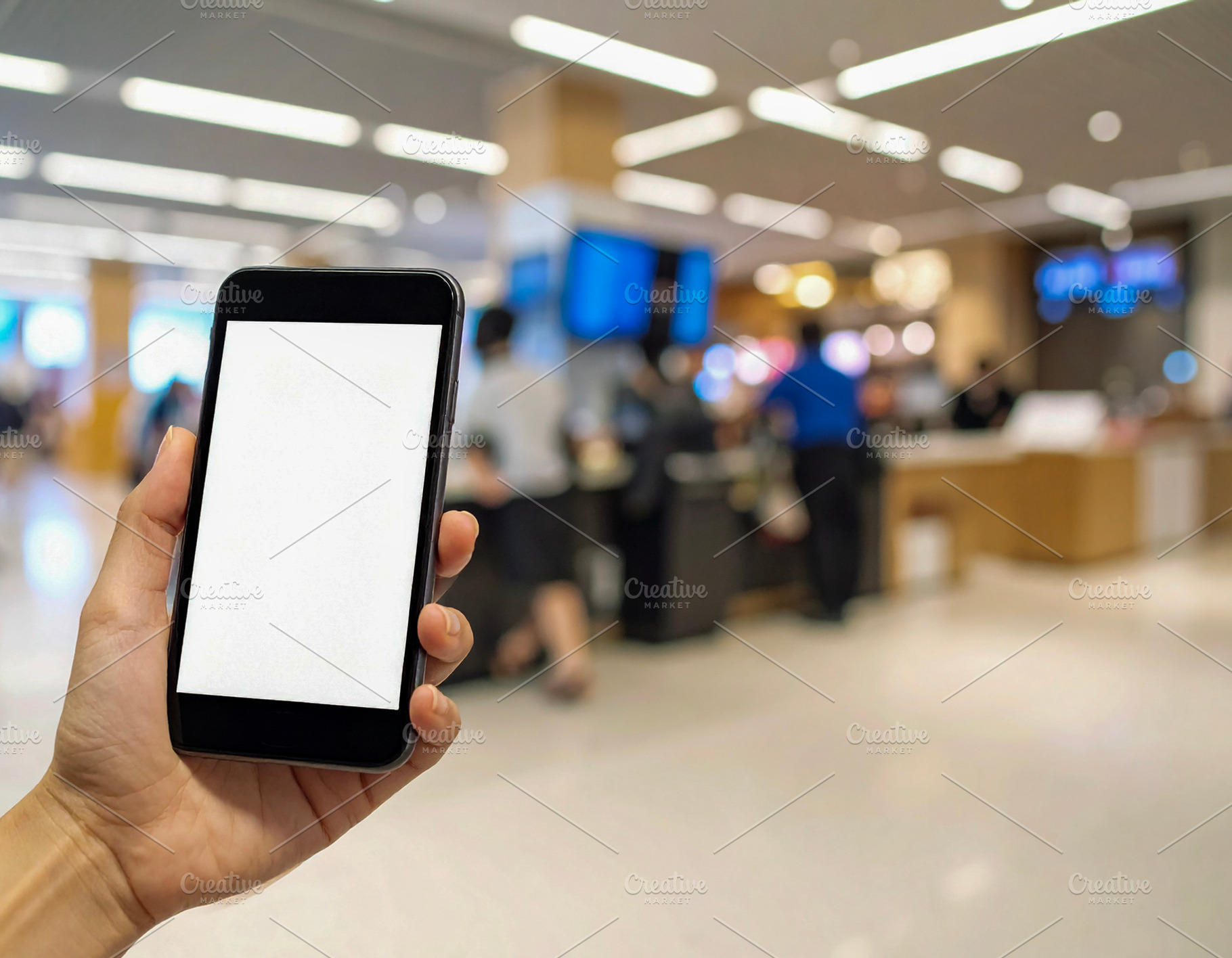 Hand holding smartphone in shopping mall lobby, a Technology Photo by DanFLCreativo