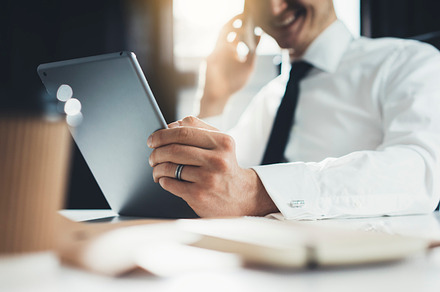Smiling businessman using tablet pc, a Business Photo by ImYanis