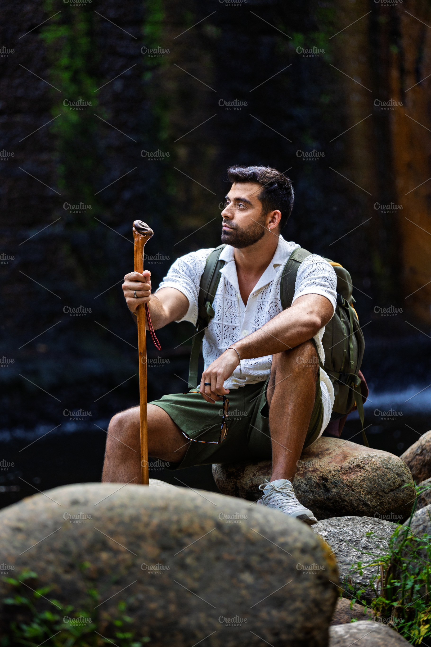 Explorer resting on rocks by a water, a Person Photo by Perpis