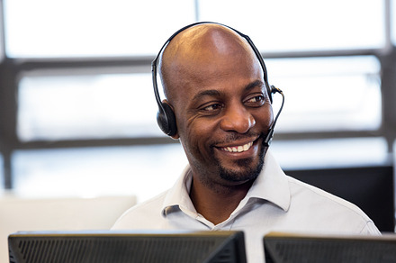Man working on computer with headset, a Photo by wavebreak
