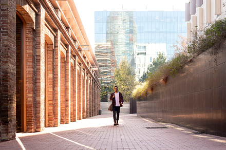 Front view of a attractive young man holding shoulder bag walking through the c, a Person Photo by RF Images