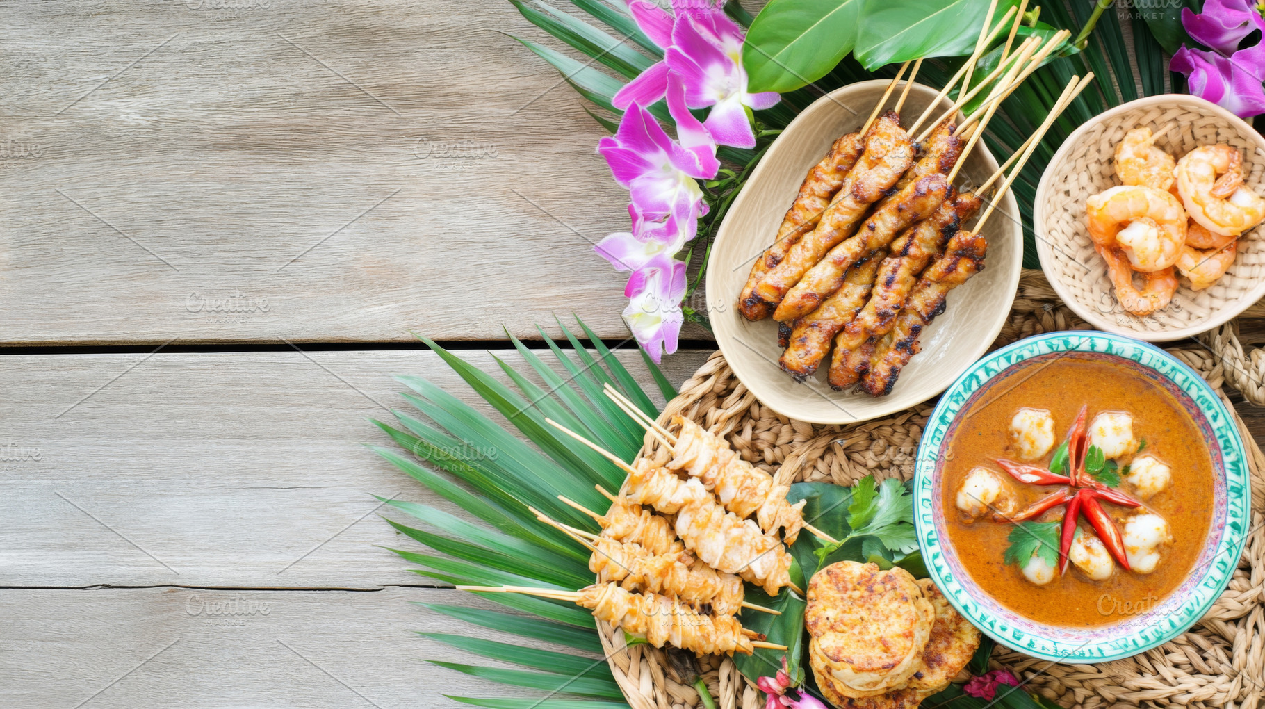 Satay skewers and shrimp with rice, sauces, and orchids arranged, a Photo by Dvoevnore photos