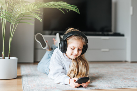 Little girl listening music lying on the floor, a Person Photo by Olena Rudo