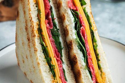 Two homemade sandwiches with sausage, cheese and arugula on a light concrete ba, a Food & Drink Photo by Budarinphoto