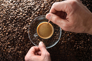 Hands stirring freshly brewed coffee over heap of coffee beans, a Food & Drink Photo by Davizro's Market