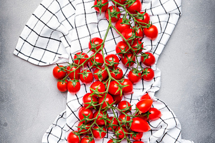 Red cherry tomatoes on branches on checkered kitchen towel on gr, a Food & Drink Photo by 5PH