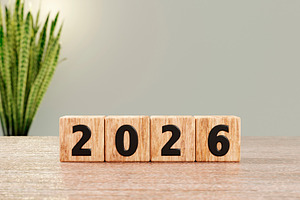 Wooden blocks show 2026 on desk with soft plant background, a Background Photo by RF Images