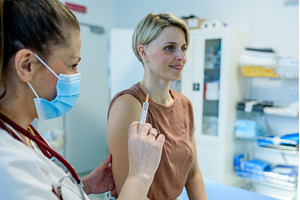 Doctor administering vaccine to, a Health & Medical Photo by HalfPoint