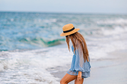 Adorable young girl with beautiful long hair enjoy tropical beach vacation. The