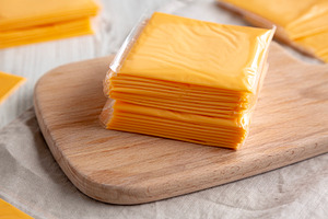 Stack of American Cheese Slices in Wrappers, side view. Close-up, a Food & Drink Photo by LiudmylaChuhunova