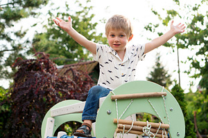Smiling boy raises arms atop backyar, a Person Photo by Elena Vagengeim