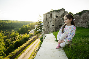 Young girl sitting by ancient ruins surrounded by scenic landscape, a Person Photo by AS photostudio