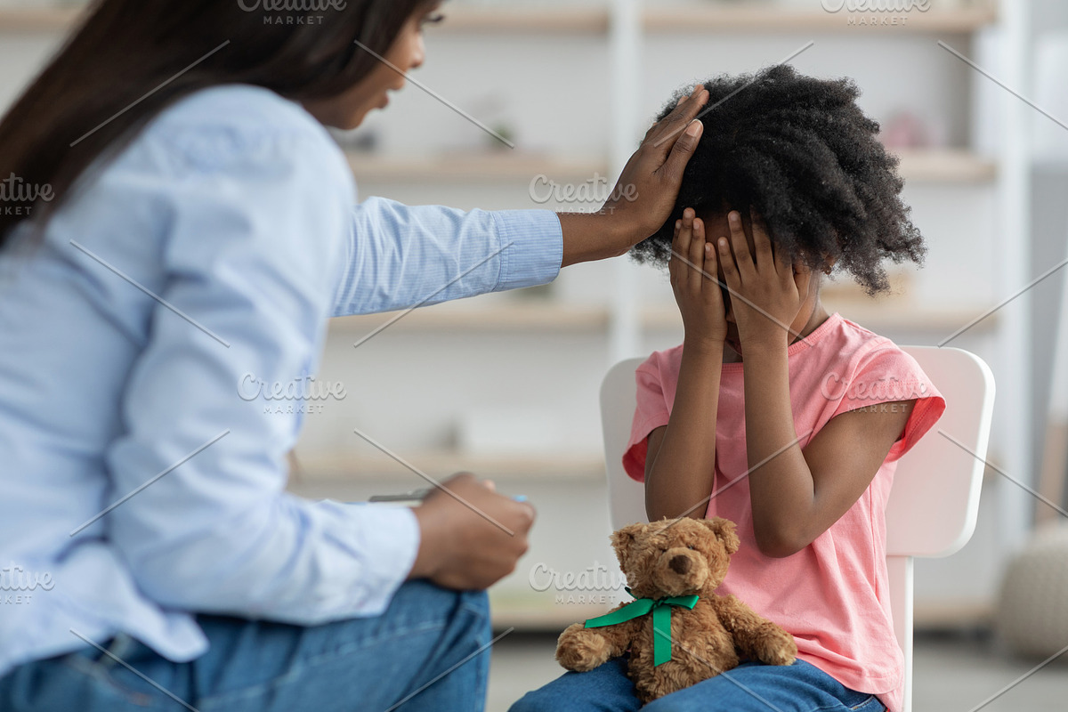 African american woman comforting emotional curly girl preschooler, clinic inte, a Photo by Prostock-Studio (Photo 2 of 2)