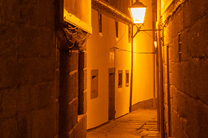 Narrow dim alley with warm lantern light at night, guimaraes, po, a Photo by DanFLCreativo