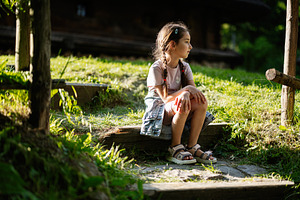 Young girl sitting on steps outdoors in a serene countryside setting, a Person Photo by AS photostudio