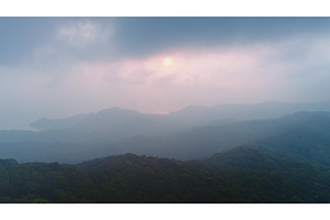 Sun setting behind misty mountains, a Nature Photo by Goinyk