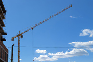 Wide view of a yellow tower crane next to a concrete building un, an Industrial Photo by Ales Munt