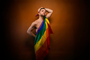 Gay man proudly holding lgbt flag acknowledging identity, a Photo by karrastock