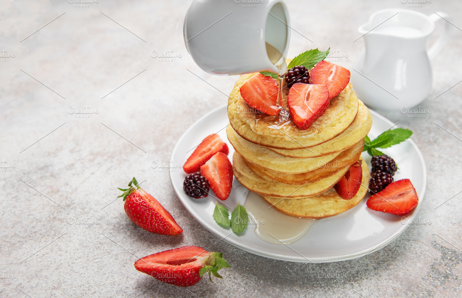 Pancakes with berries and syrup pouring for breakfast, a Food & Drink Photo by Olena Rudo